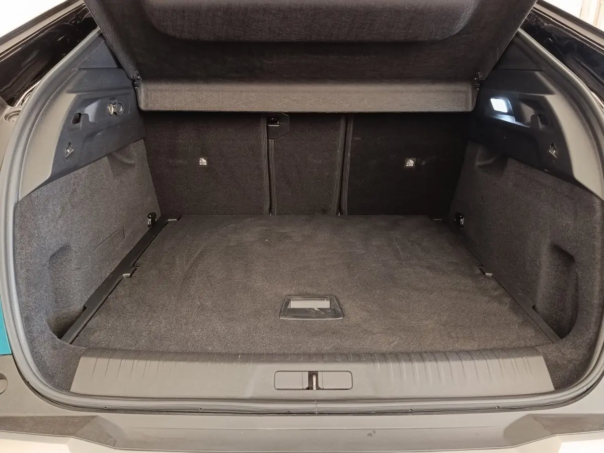 Coffre ouvert du Peugeot 3008 hybride bleu, vue arrière montrant un espace de chargement spacieux et tapis noir.