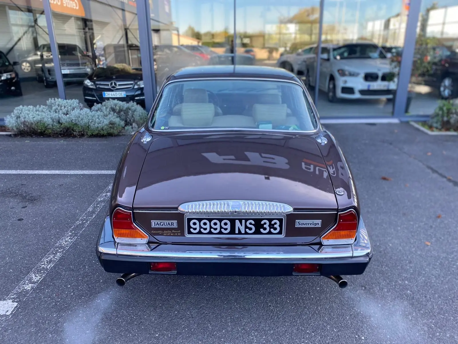 Vue arrière d'une Jaguar XJ6 Série 3 4.2 Sovereign marron de 1985 avec double sortie d'échappement et plaques françaises.