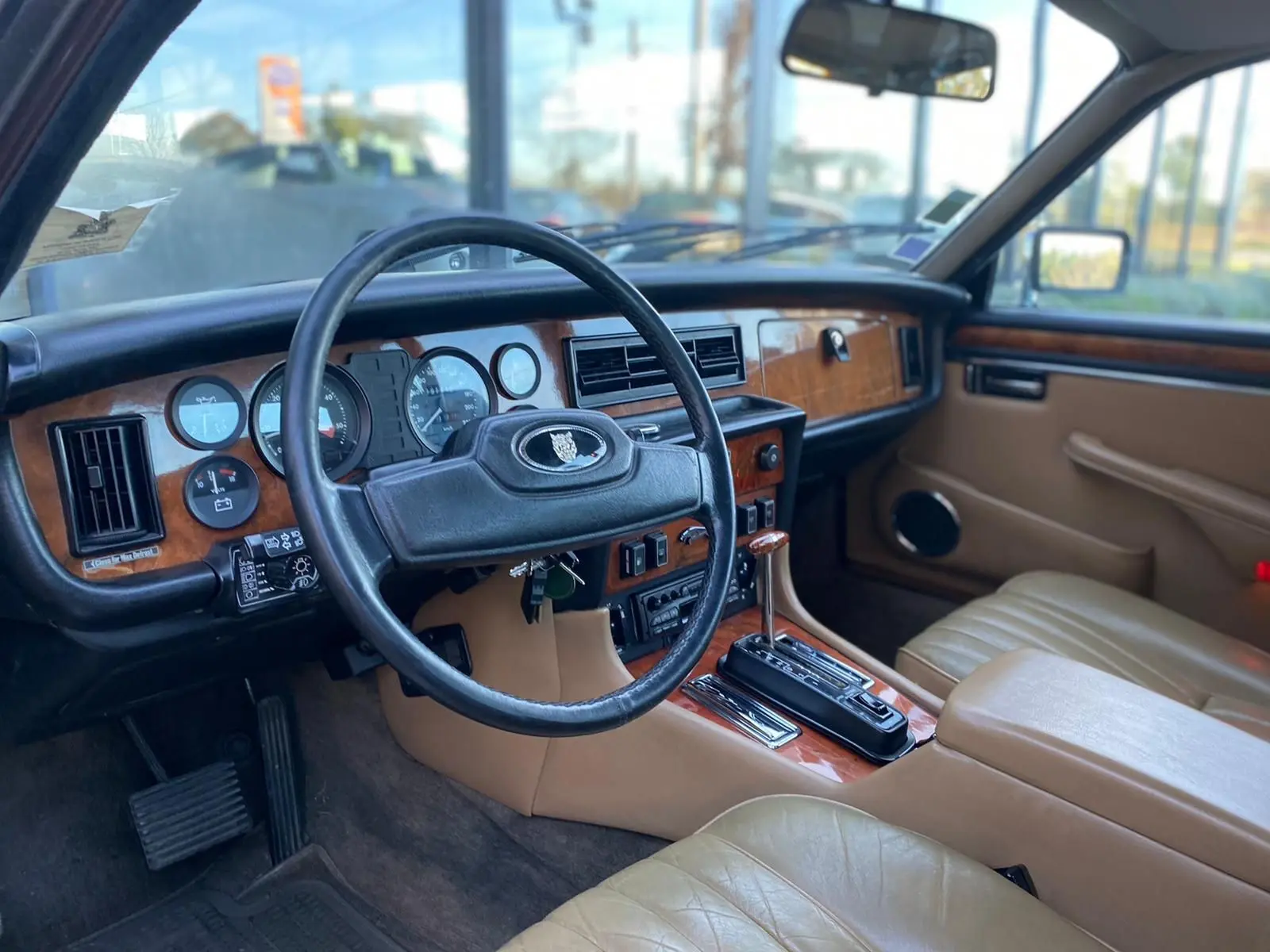 Intérieur beige et bois d'une Jaguar XJ6 Série 3 4.2 Sovereign 1985, vue côté conducteur avec volant et tableau de bord.