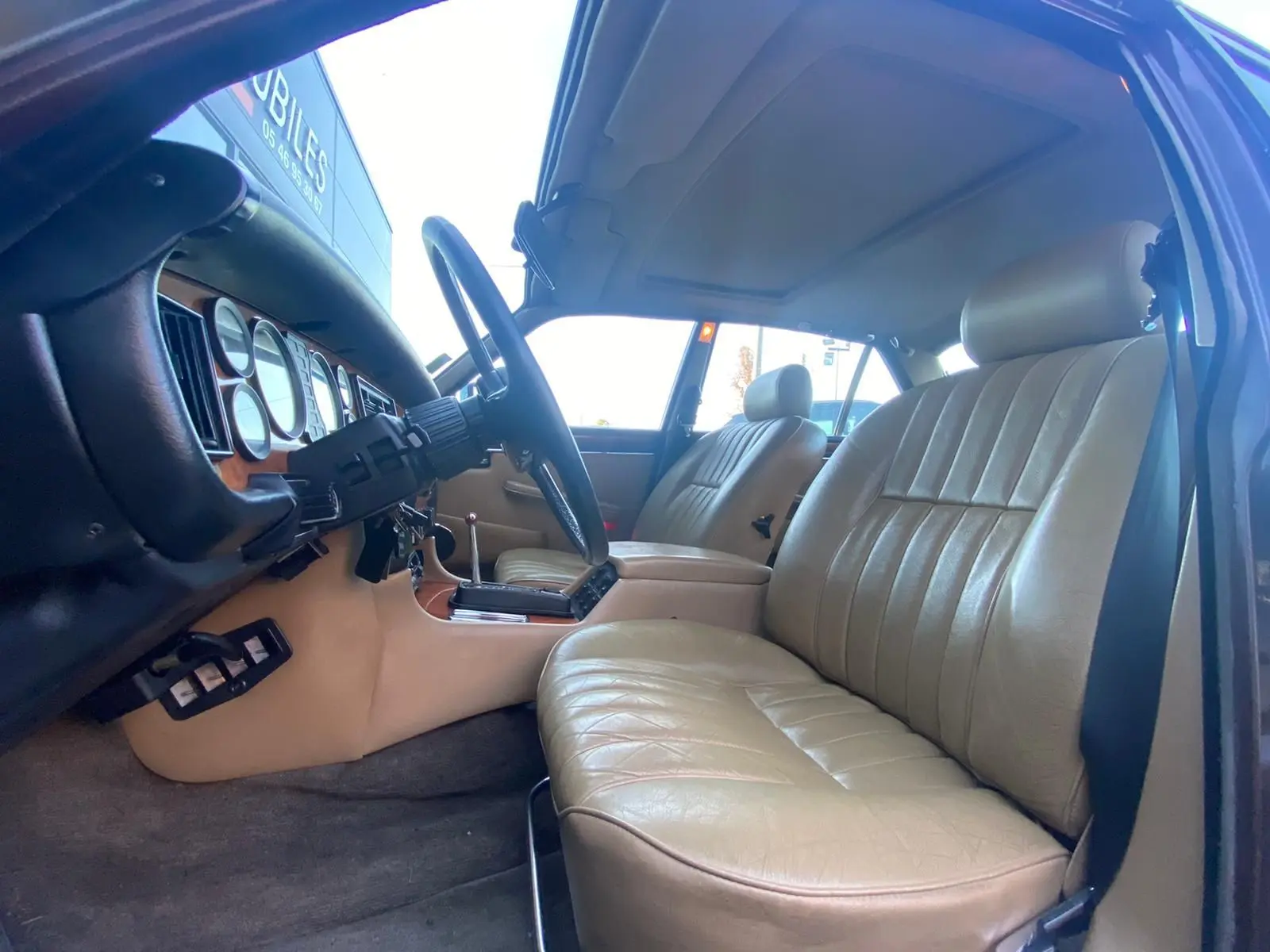 Intérieur beige cuir d'une Jaguar XJ6 Série 3 4.2 Sovereign 1985, vue côté conducteur avec tableau de bord bois.