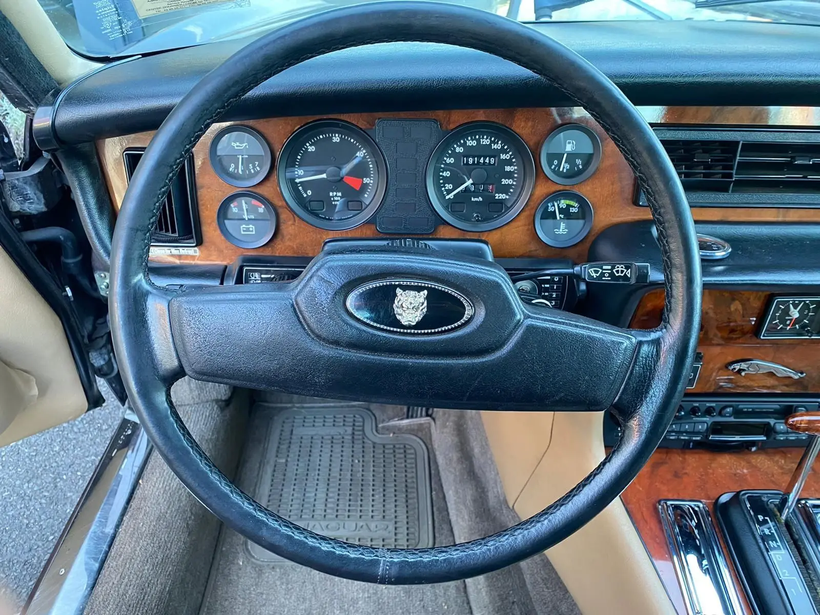 Vue intérieure centrée sur le volant noir et le tableau de bord en bois de la Jaguar XJ6 Série 3 marron de 1985.