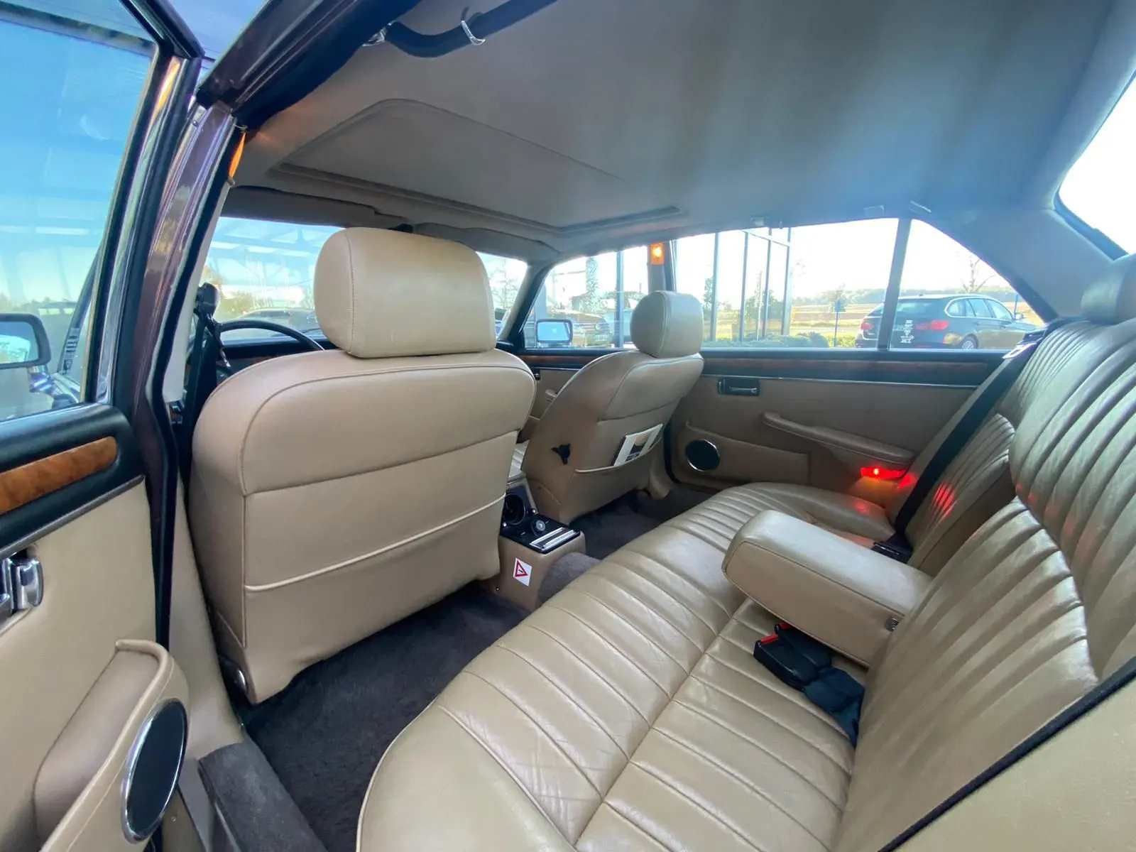 Vue intérieure arrière droite d'une Jaguar XJ6 Série 3 4.2 Sovereign 1985 avec sellerie cuir beige et finitions bois.