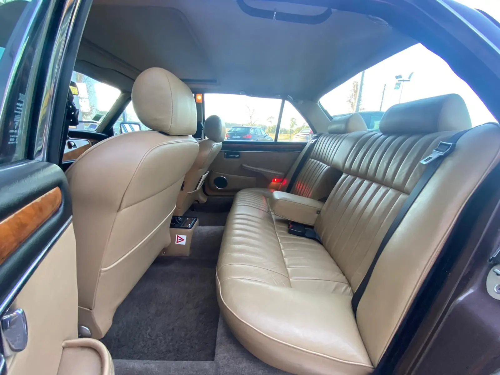 Vue intérieure arrière côté droit d'une Jaguar XJ6 Série 3 4.2 Sovereign 1985, sellerie cuir beige et boiseries apparentes.
