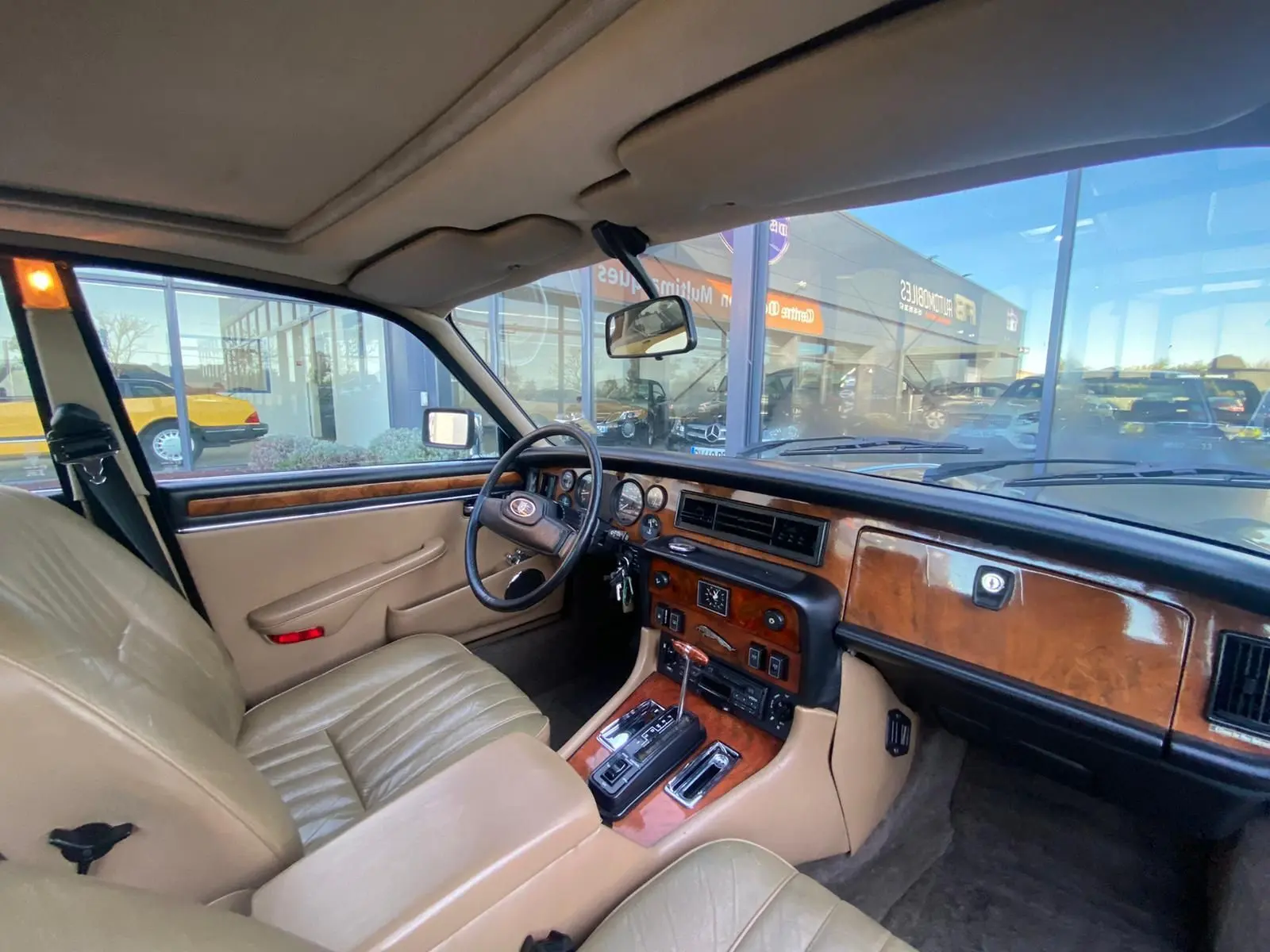 Intérieur beige et bois d'une Jaguar XJ6 Série 3 4.2 Sovereign 1985, vue côté conducteur avec tableau de bord classique.