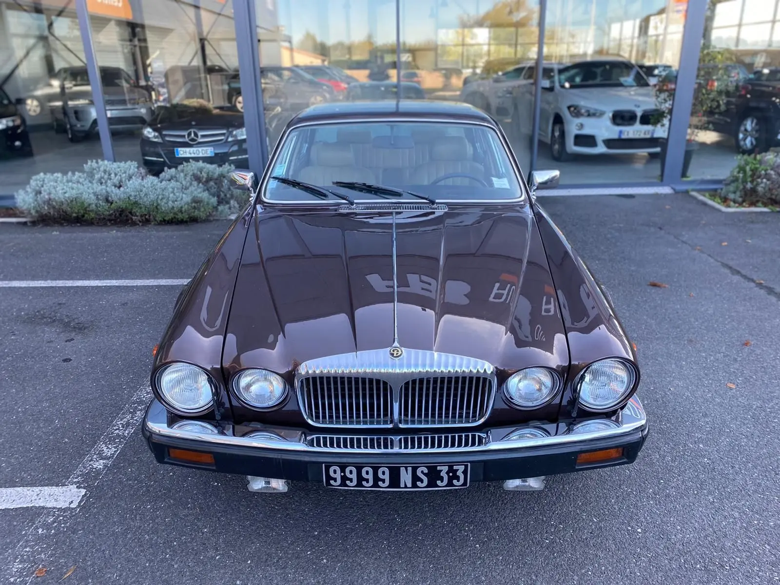 Vue avant d'une Jaguar XJ6 Série 3 4.2 Sovereign marron de 1985 avec calandre chromée et phares ronds doubles.