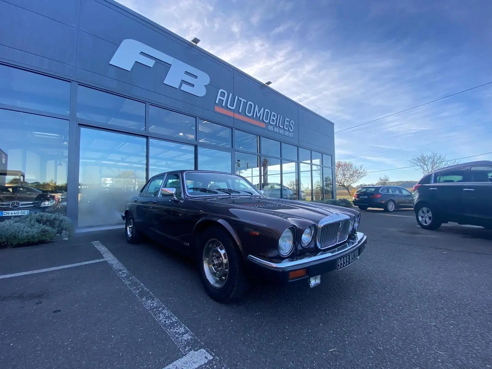 Jaguar XJ6 Série 3 4.2 Sovereign marron vue 3/4 avant droit, garée devant un concessionnaire FB Automobiles.