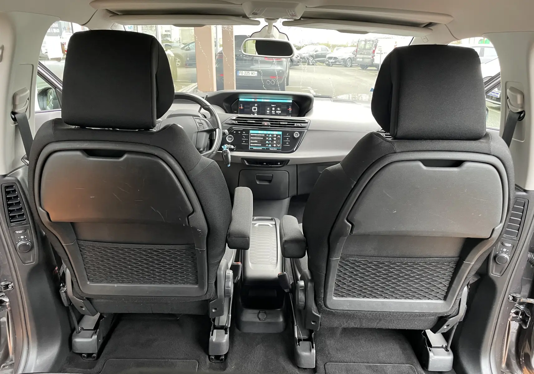 Vue intérieure arrière du Citroën Grand C4 Picasso gris 2018, montrant les sièges avant et le tableau de bord avec écran tactile.