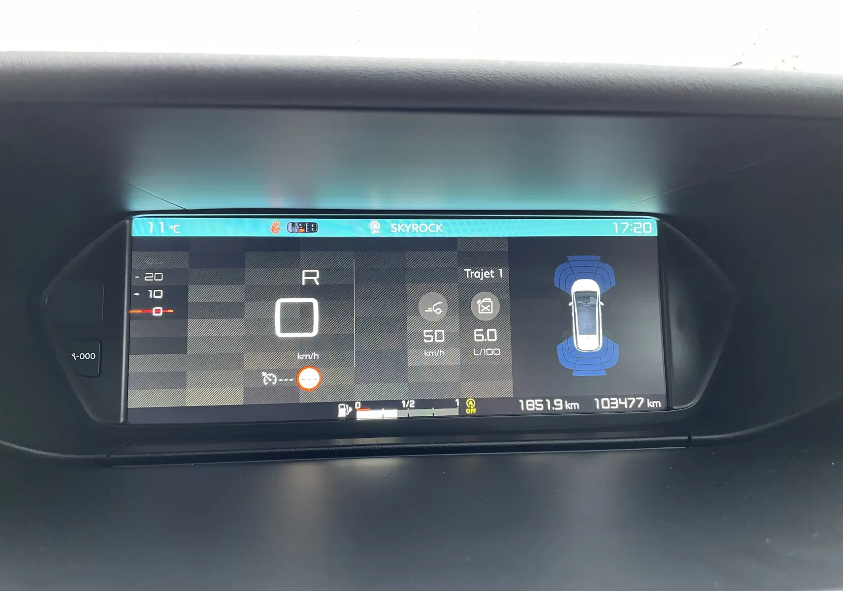 Affichage numérique du tableau de bord du Citroën Grand C4 Picasso gris, montrant vitesse, consommation et capteurs de proximité.