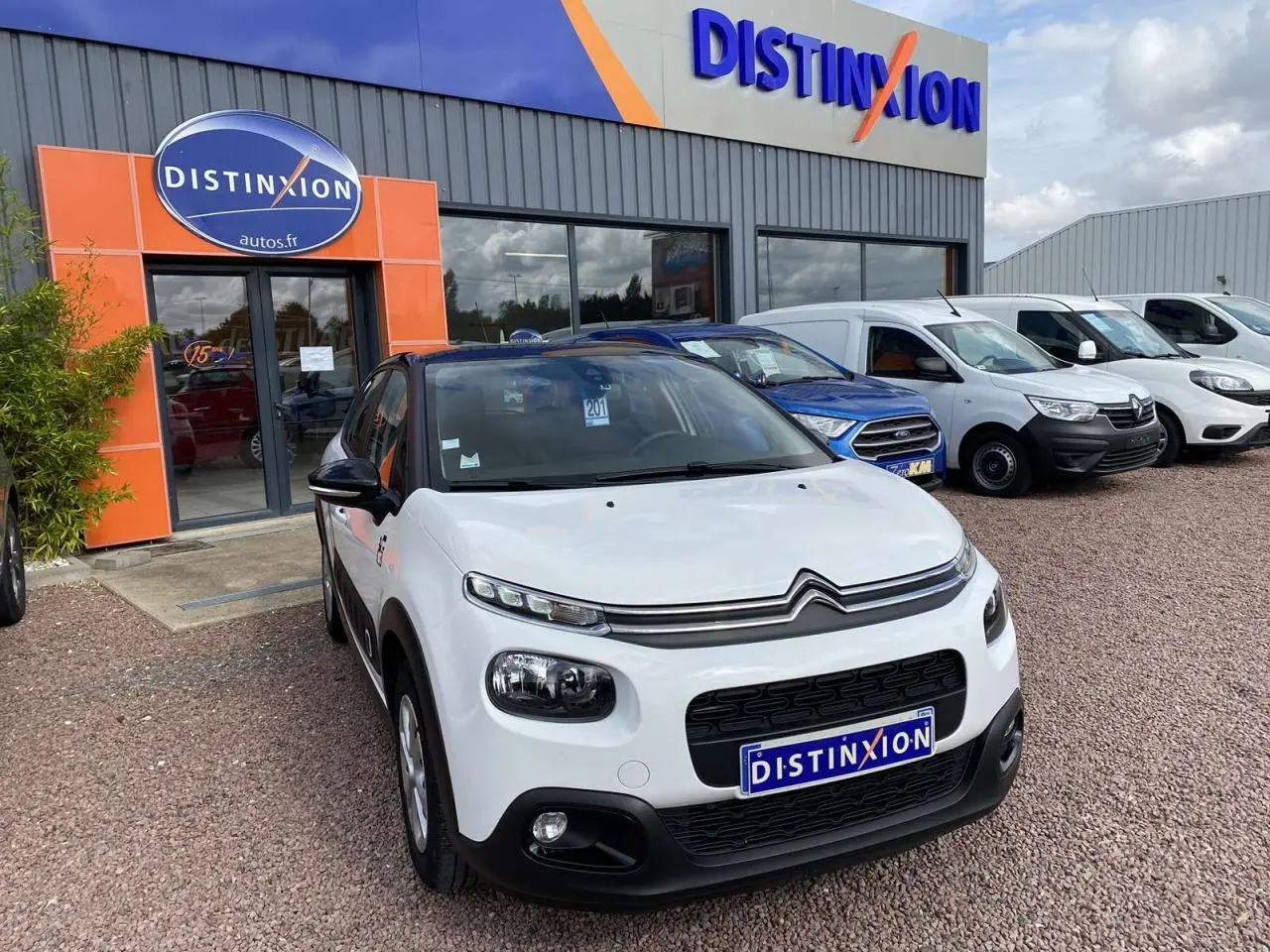 Citroën C3 blanc vue 3/4 avant avec toit noir, stationnée devant un concessionnaire Distinxion.