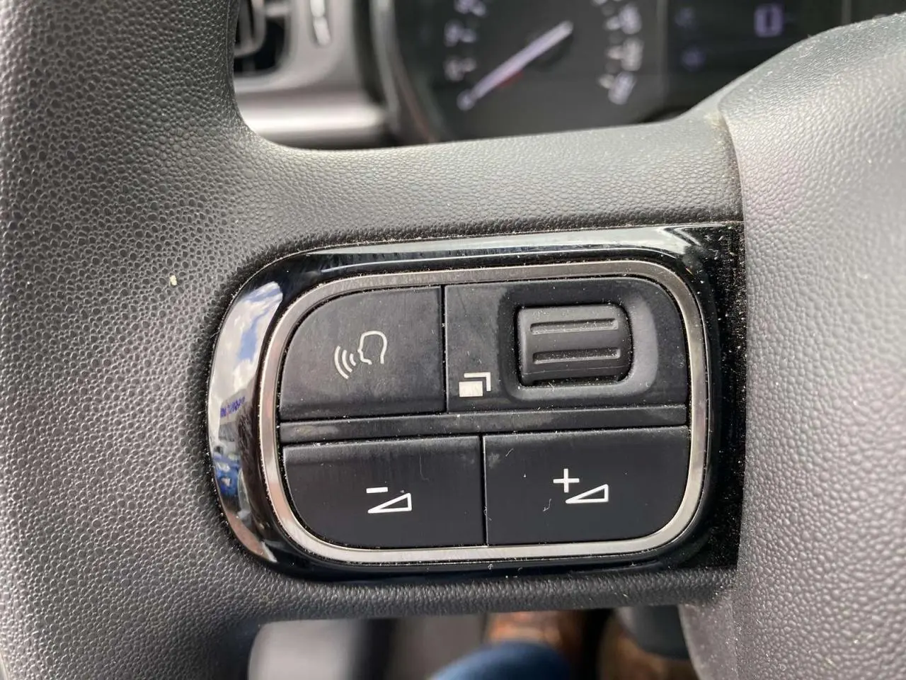 Gros plan sur les commandes vocales et volume au volant d'une Citroën C3 blanche 2019 essence.