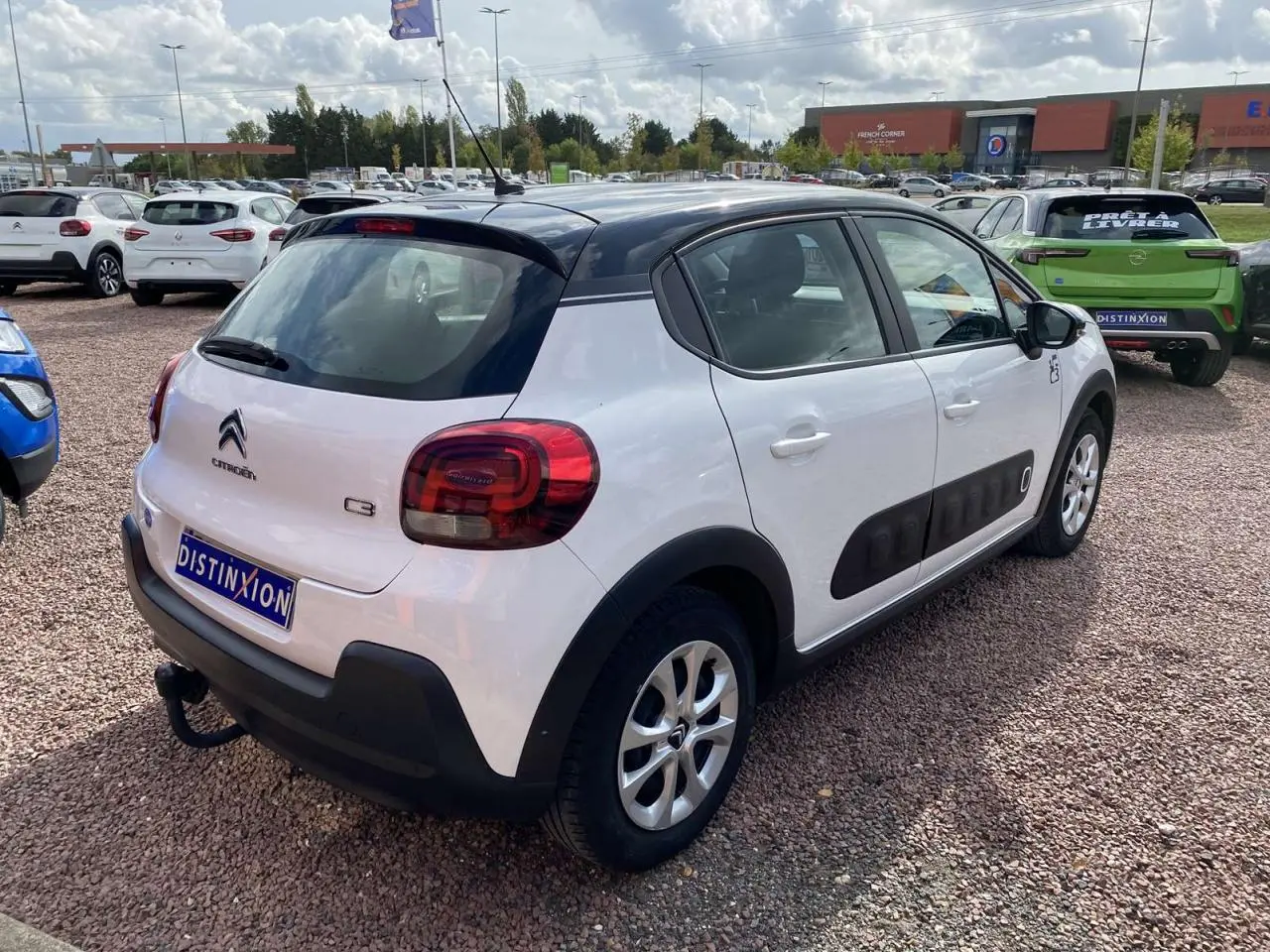 Citroën C3 blanc avec toit noir, vue 3/4 arrière droit, équipée d'un attelage et de protections latérales noires.