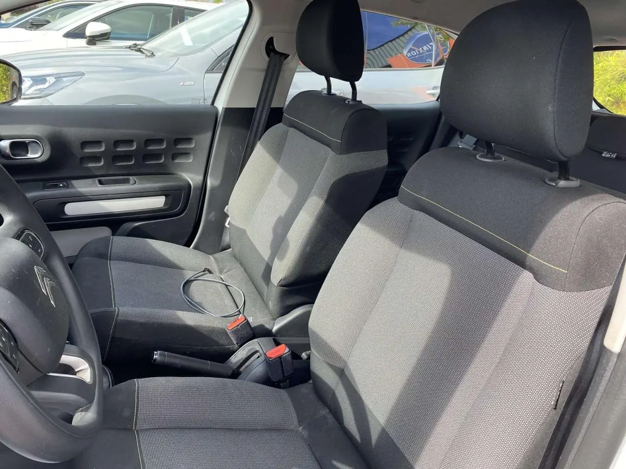 Intérieur avant de la Citroën C3 blanche 2019, vue côté gauche montrant les sièges tissu gris et le volant.