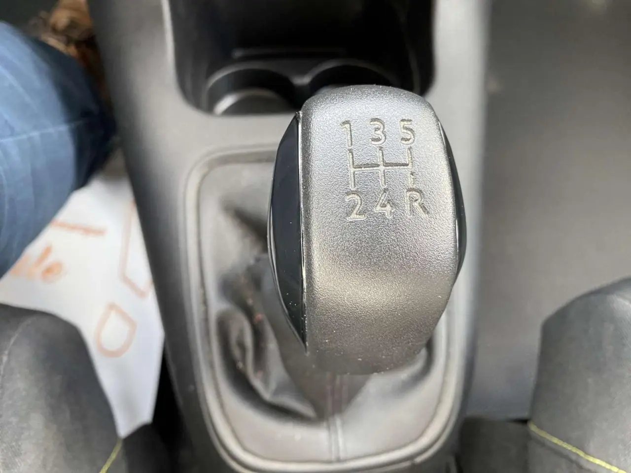 Le levier de vitesses manuel noir de la Citroën C3 blanche vue de dessus, montrant les rapports 5 vitesses plus marche arrière.