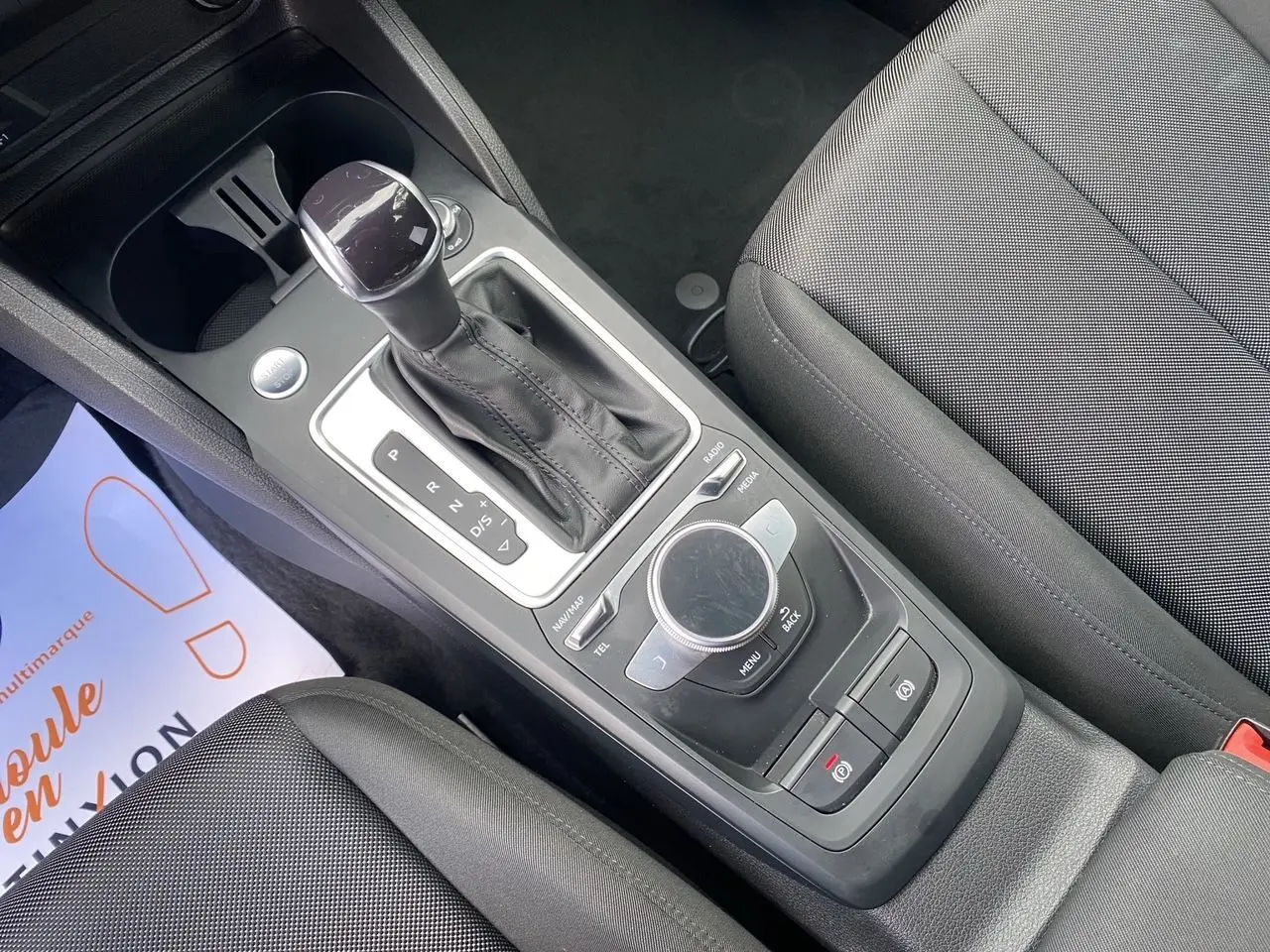 Vue rapprochée de la console centrale noire avec levier de vitesses automatique et molette de commande multimédia d'un Audi Q2.