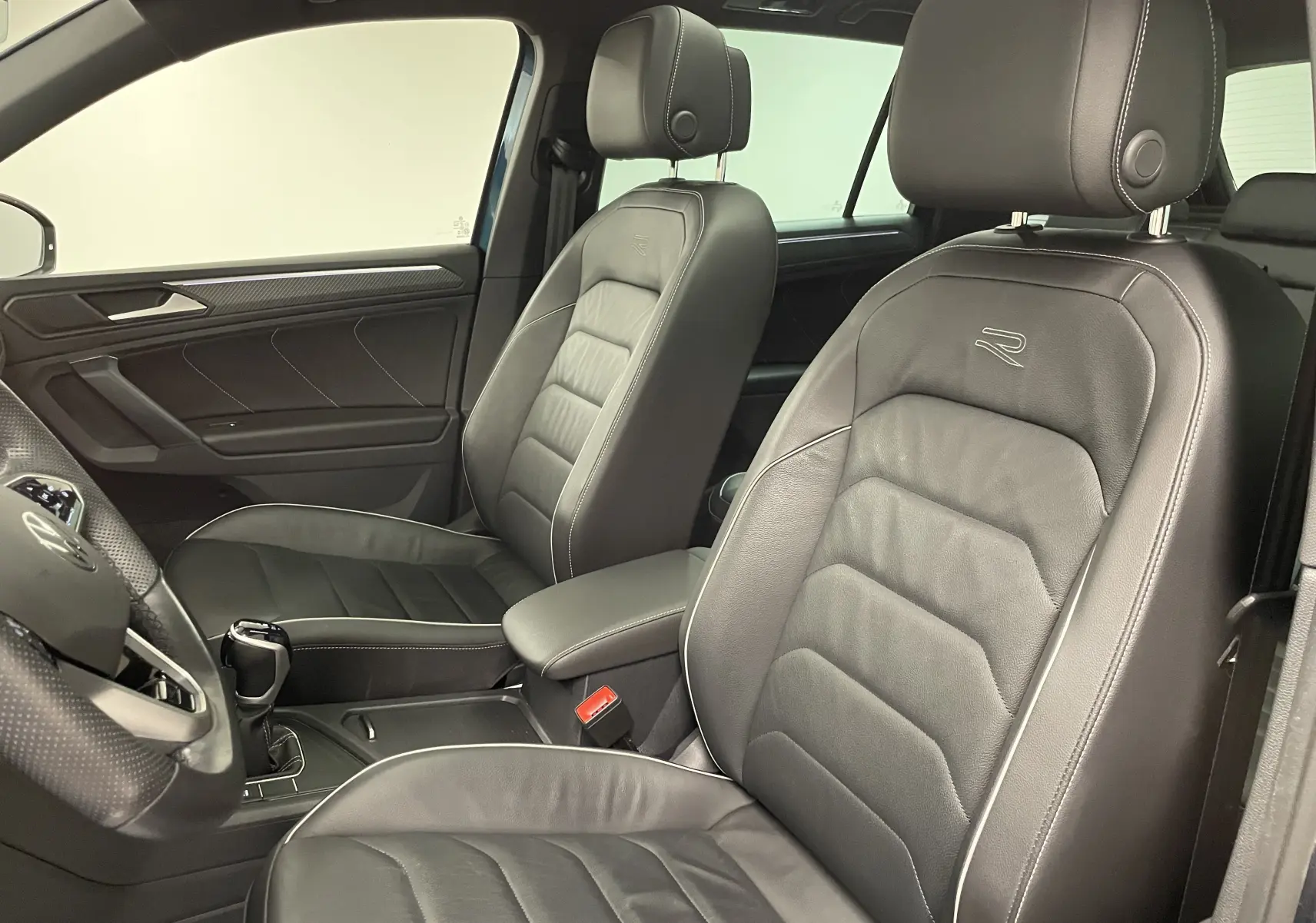 Intérieur du Volkswagen Tiguan 2024 vu côté gauche, sièges en cuir noir avec logo R et finitions soignées.