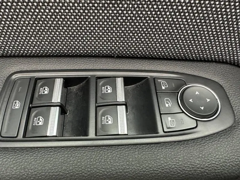 Gros plan sur les commandes de lève-vitres et réglages des rétroviseurs côté conducteur du Renault Captur noir 2025.