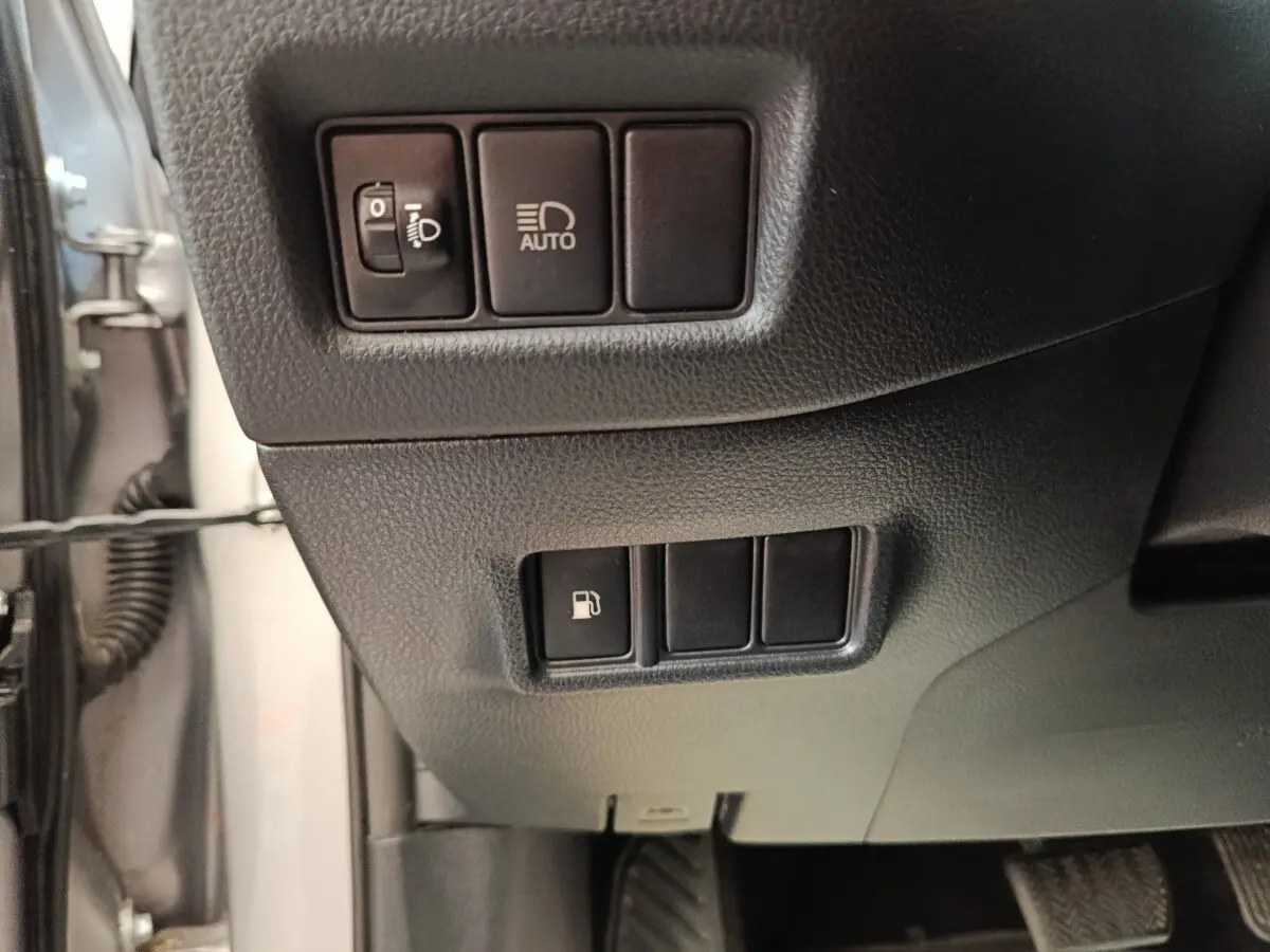 Gros plan sur les commandes côté gauche du tableau de bord du Toyota C-HR gris clair, avec interrupteurs phares et ouverture réservoir.