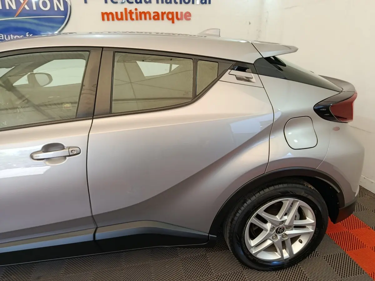 Vue latérale droite du Toyota C-HR gris clair 2.0 Hybride 184 avec jante alliage et lignes anguleuses marquées.