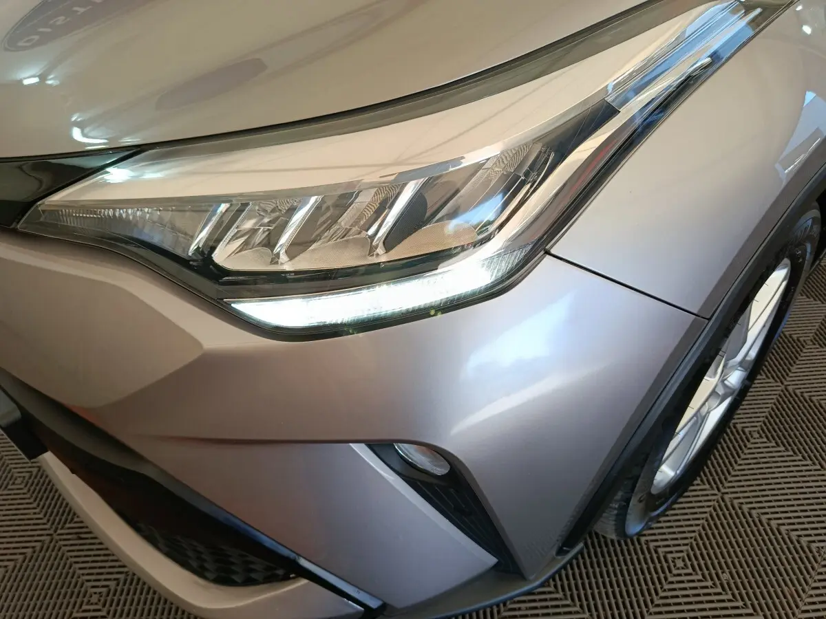 Gros plan sur le phare avant droit du Toyota C-HR gris clair 2022 avec détails LED et partie de la roue.