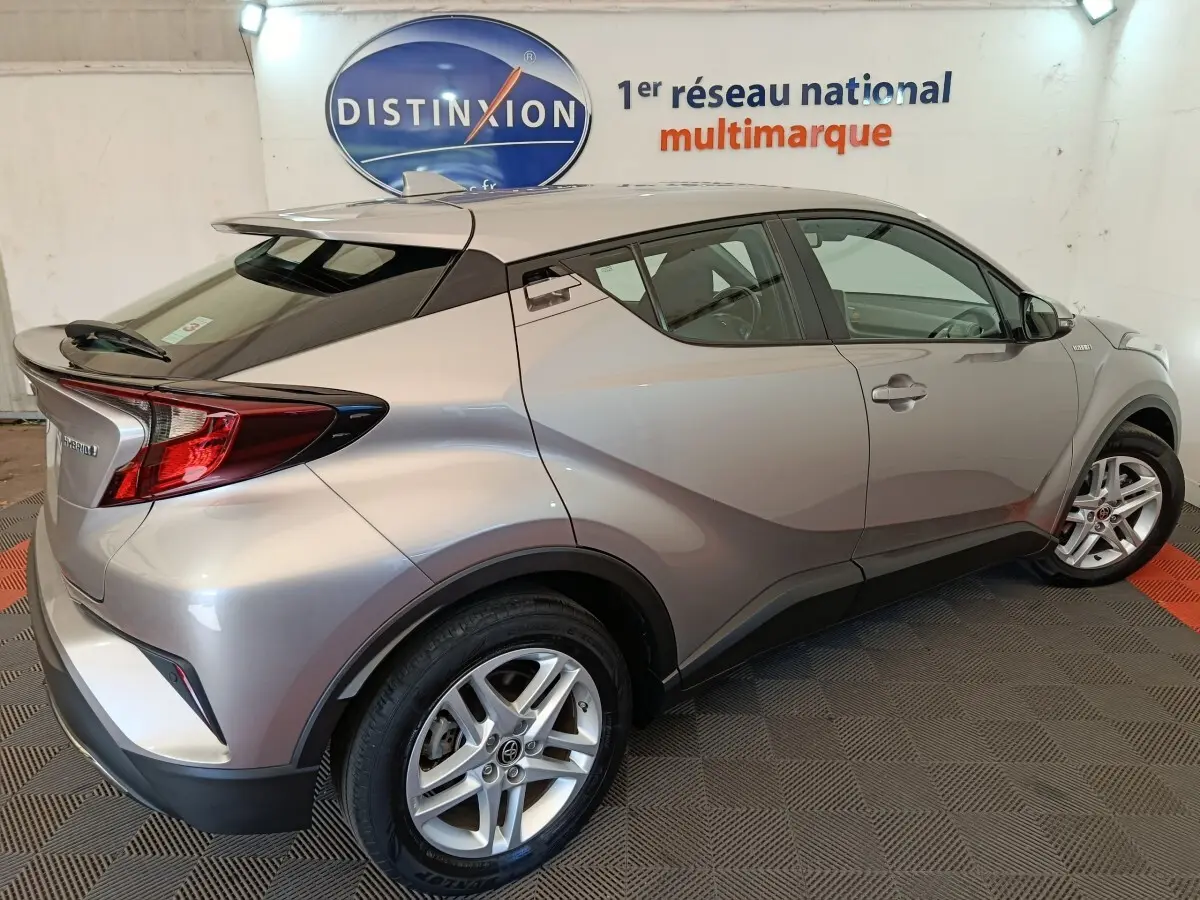Vue 3/4 arrière droite du Toyota C-HR gris clair hybride 2022 avec toit noir et jantes alliage.