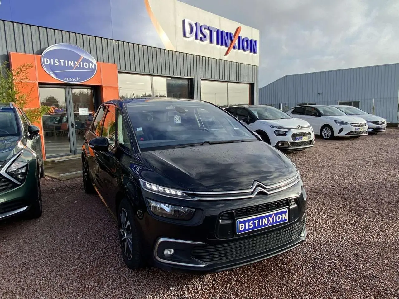 Citroën C4 Spacetourer noir en 3/4 avant droit avec jantes alliage bi-ton, stationné devant un concessionnaire Distinxion.