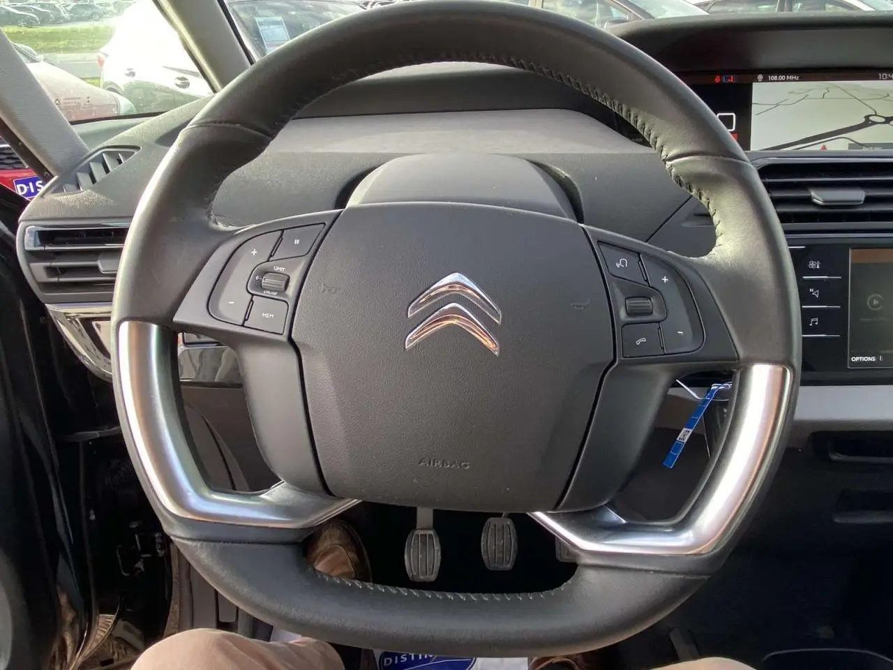 Volant cuir noir avec commandes intégrées sur Citroën C4 Spacetourer 2019, tableau de bord et écran tactile visibles en arrière-plan.