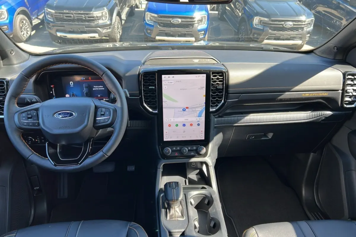 Intérieur du Ford Ranger 3.0 V6 240 Wildtrak Plus 2025, vue tableau de bord avec écran tactile vertical et volant multifonction.