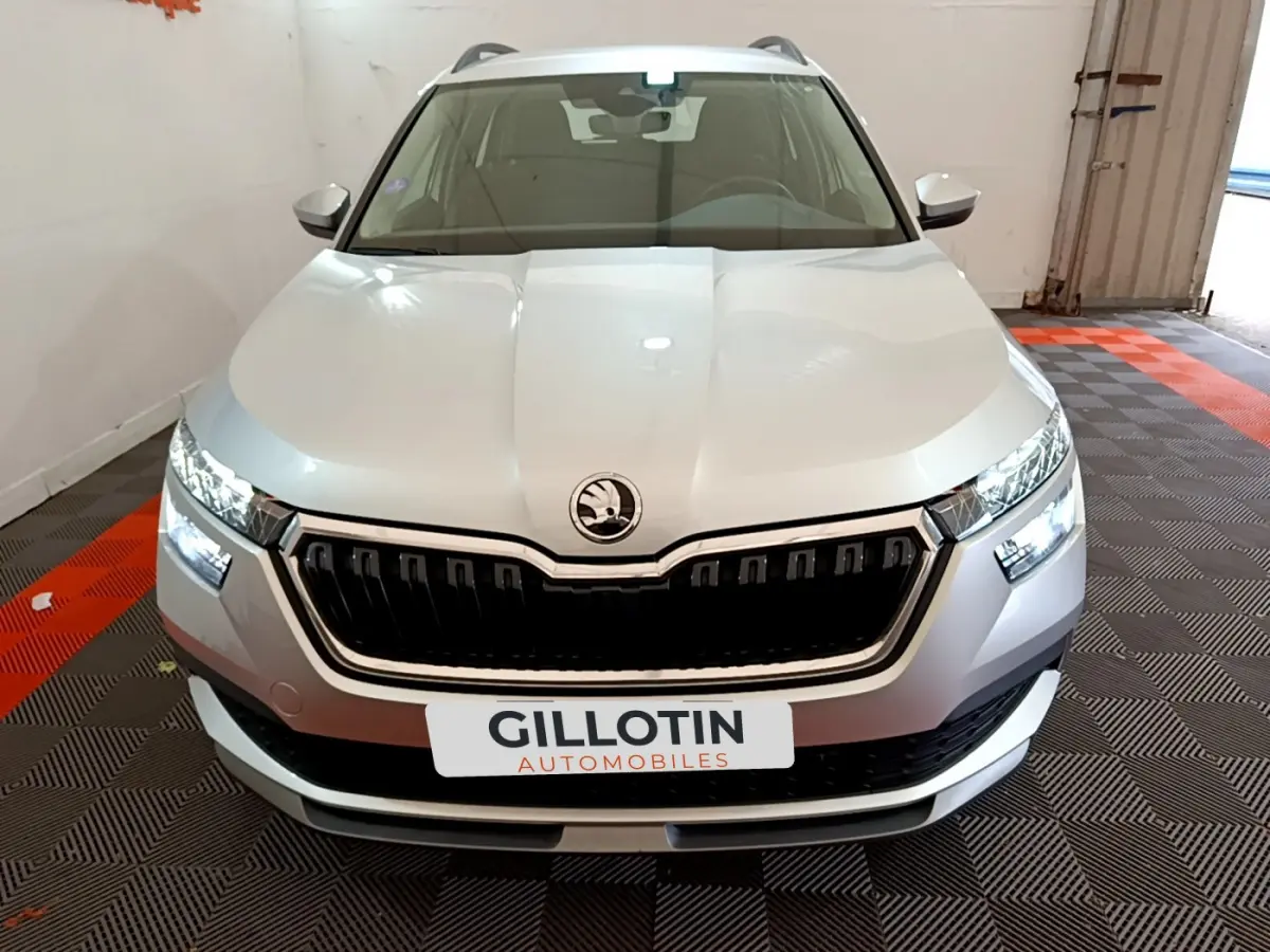 Vue frontale d'un Skoda Kamiq gris clair avec calandre noire et phares LED allumés en intérieur.