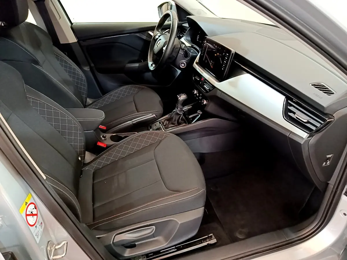 Intérieur côté conducteur du Skoda Kamiq gris clair 2022, sièges noirs avec surpiqûres et tableau de bord moderne.