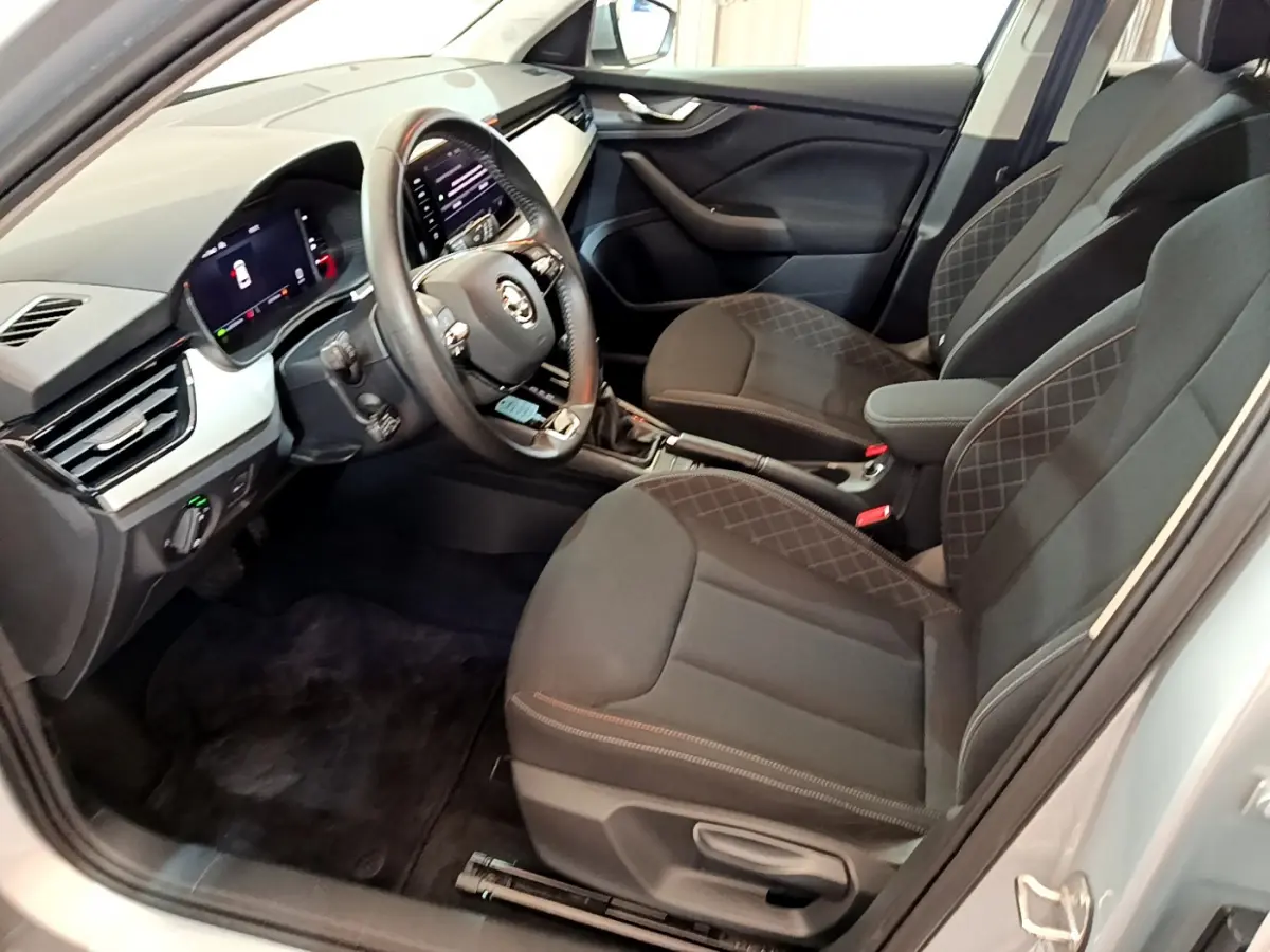 Intérieur avant droit du Skoda Kamiq gris clair 2022, sièges noirs avec surpiqûres et tableau de bord digital.