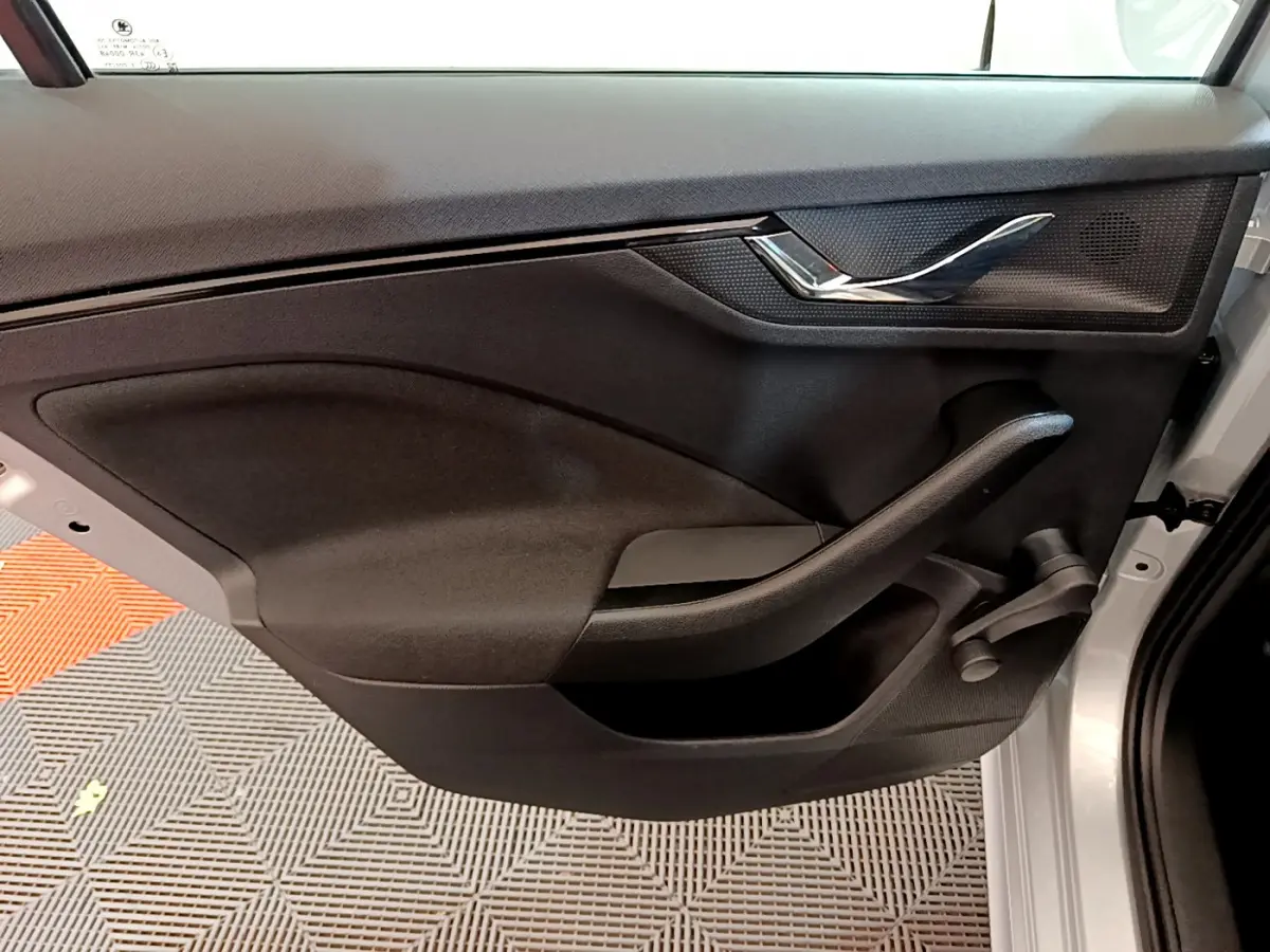 Vue rapprochée de la porte avant droite noire d'un Skoda Kamiq gris clair avec poignée chromée et manivelle de vitre.