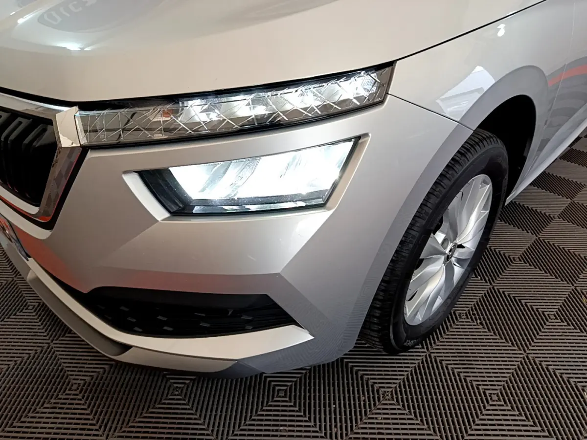 Gros plan sur l'avant droit gris clair du Skoda Kamiq 2022, mettant en valeur les phares LED et la roue alu.