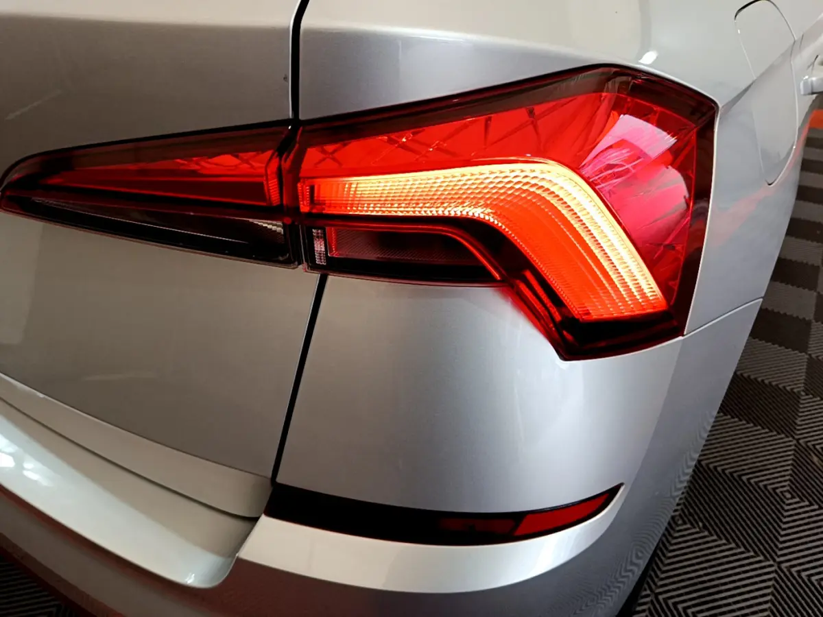 Gros plan sur le feu arrière droit rouge d’un Skoda Kamiq gris clair 2022, avec carrosserie lisse et reflets.