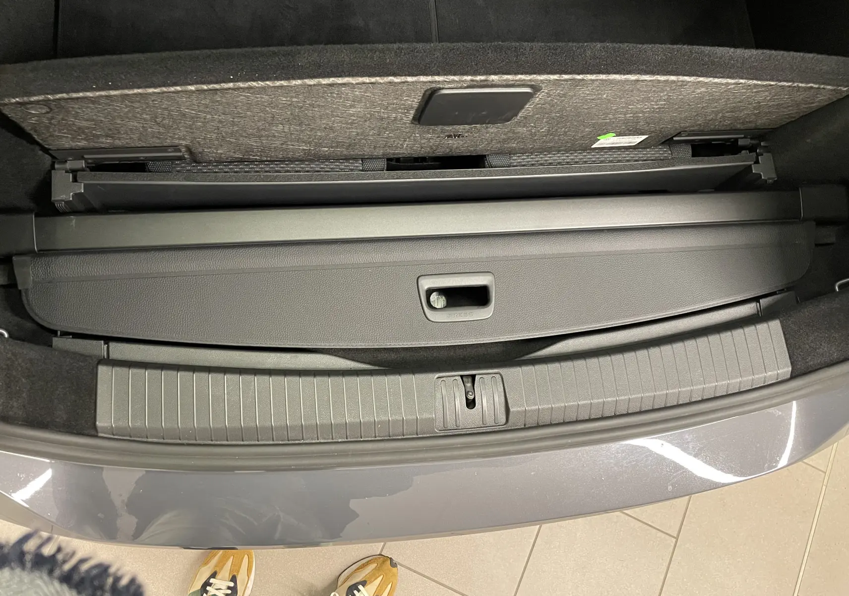 Vue plongeante sur le coffre ouvert du Volkswagen Touran gris Dauphin, montrant la plage arrière et le seuil de chargement.