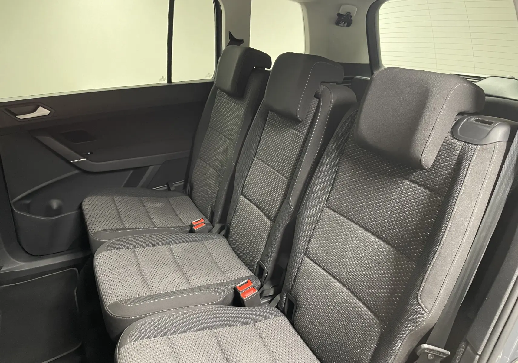 Vue intérieure côté gauche des sièges arrière en tissu gris du Volkswagen Touran 2024, version 7 places.