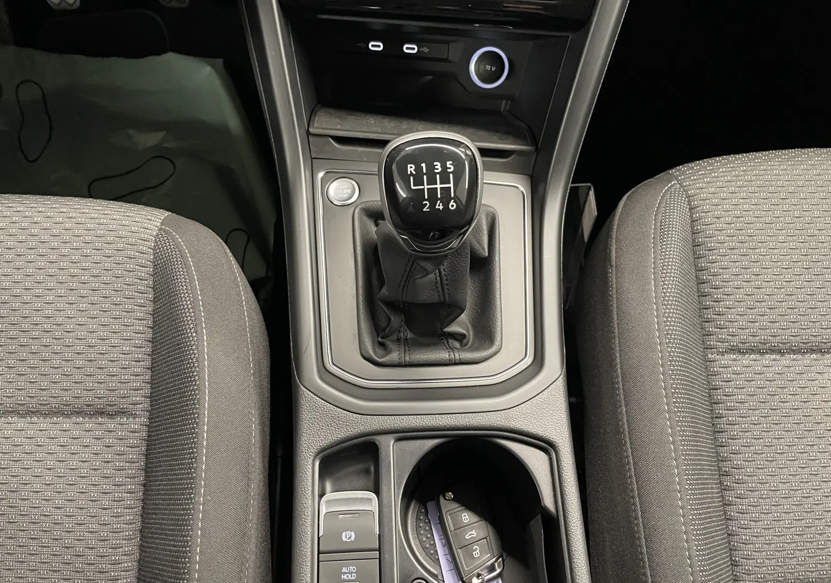 Vue intérieure centrée sur la console centrale du Volkswagen Touran 2024, levier de vitesse manuel et clé Keyless Access.