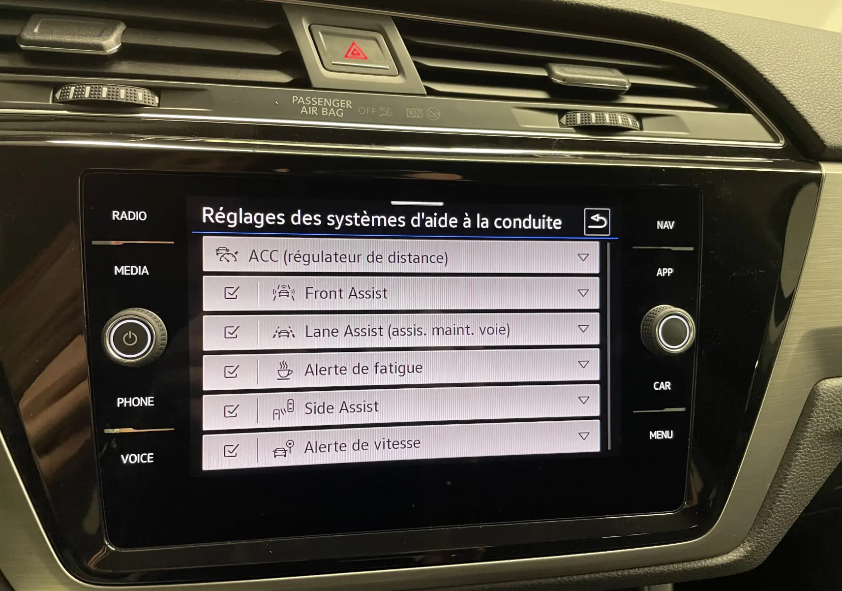Écran tactile central du Volkswagen Touran 2024 affichant les réglages des aides à la conduite, intérieur noir et beige.