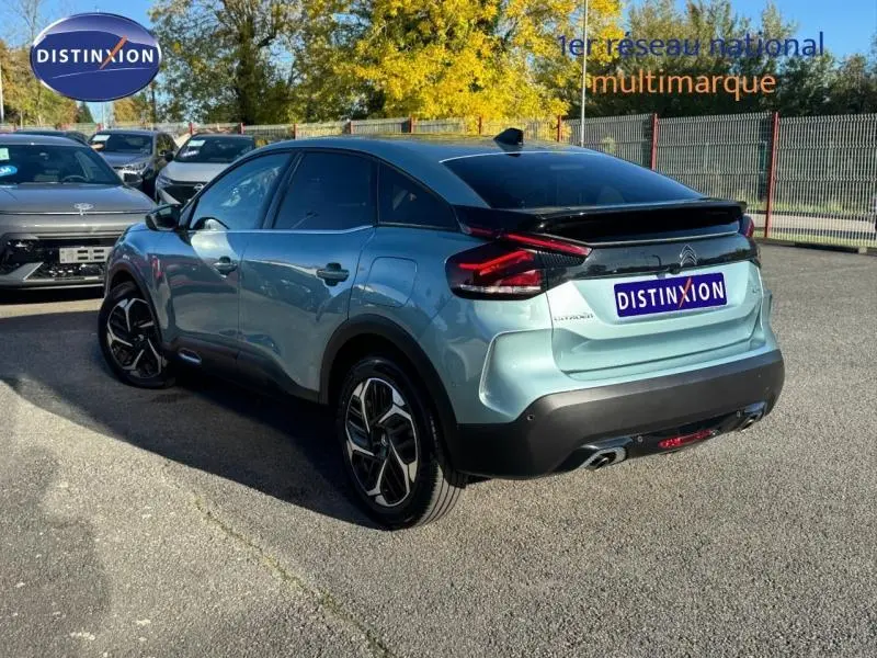 Vue 3/4 arrière droite d'une Citroën C4 gris clair 2024 avec toit noir et feux arrière LED distinctifs.