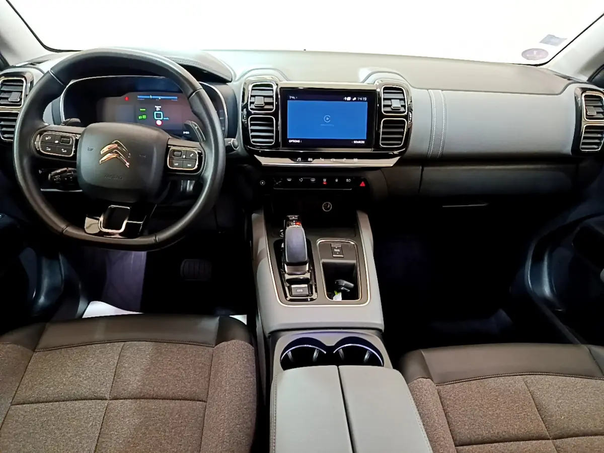 Vue intérieure avant du Citroën C5 Aircross Hybrid gris clair, avec tableau de bord numérique et écran tactile central.