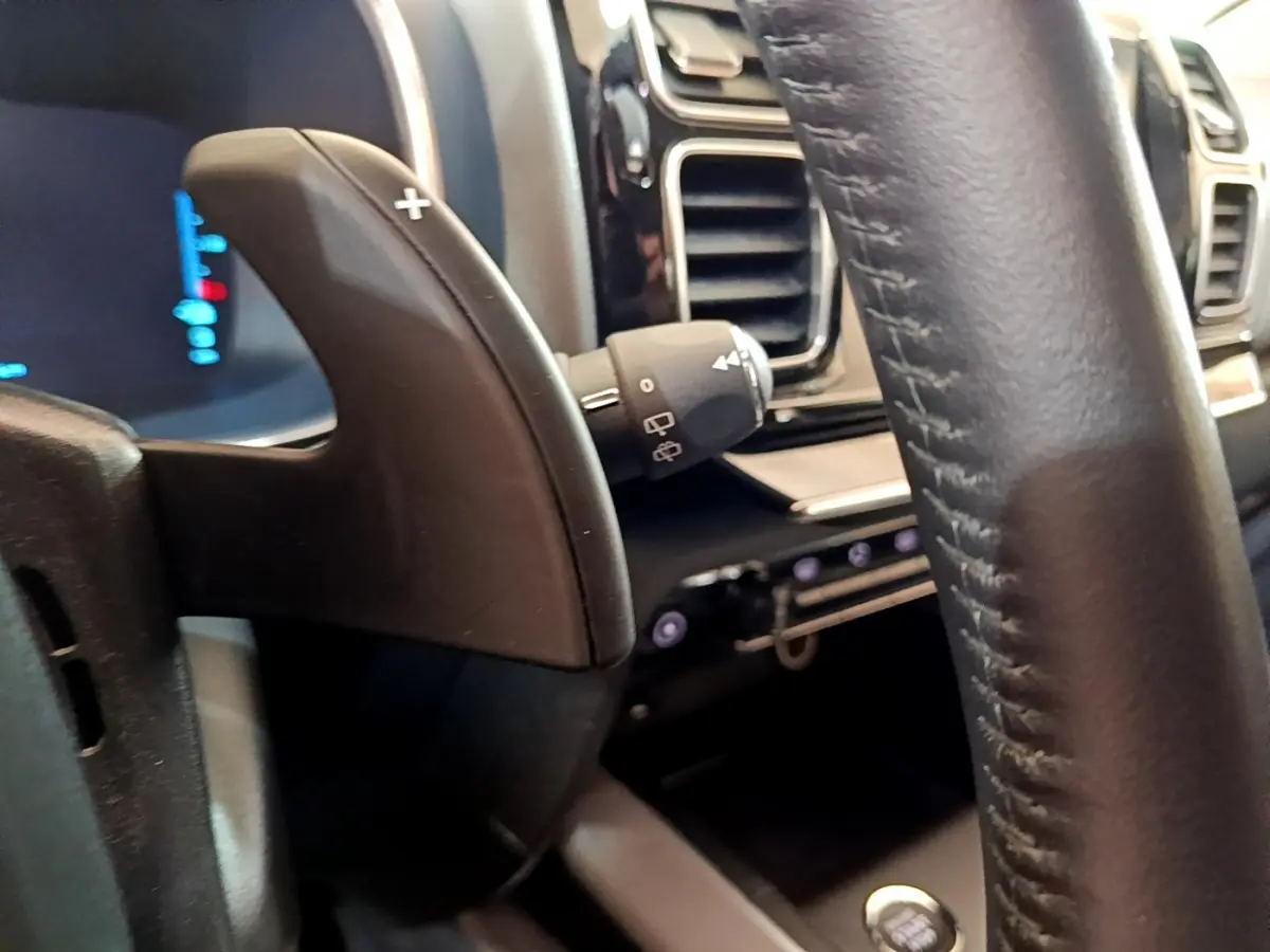 Gros plan sur la palette de changement de vitesse et le volant cuir noir du tableau de bord du Citroën C5 Aircross Hybrid 225 ë-EAT8 Business.
