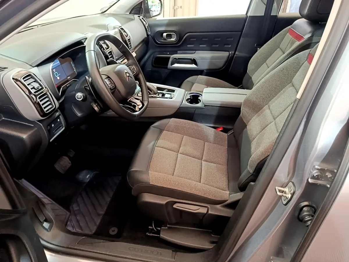 Intérieur côté conducteur du Citroën C5 Aircross Hybrid gris clair, sièges tissu et cuir, tableau de bord moderne avec écran numérique.