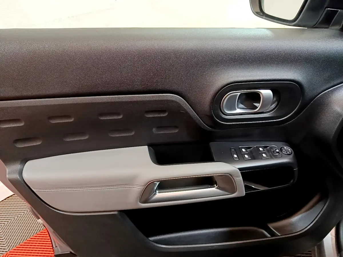 Gros plan sur la porte côté gauche du Citroën C5 Aircross Hybrid gris clair avec commandes de vitres et poignée intégrée.