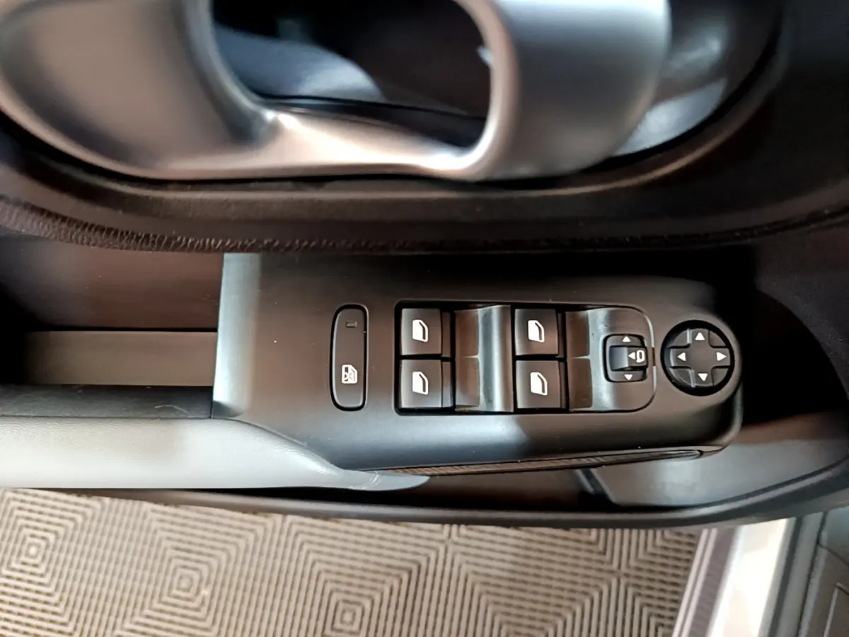 Gros plan sur la commande des vitres et rétroviseurs côté conducteur d'une Citroën C5 Aircross Hybrid gris clair.
