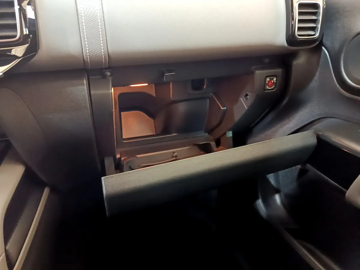 Intérieur du Citroën C5 Aircross Hybrid 225, vue rapprochée de la boîte à gants ouverte avec éclairage intérieur.