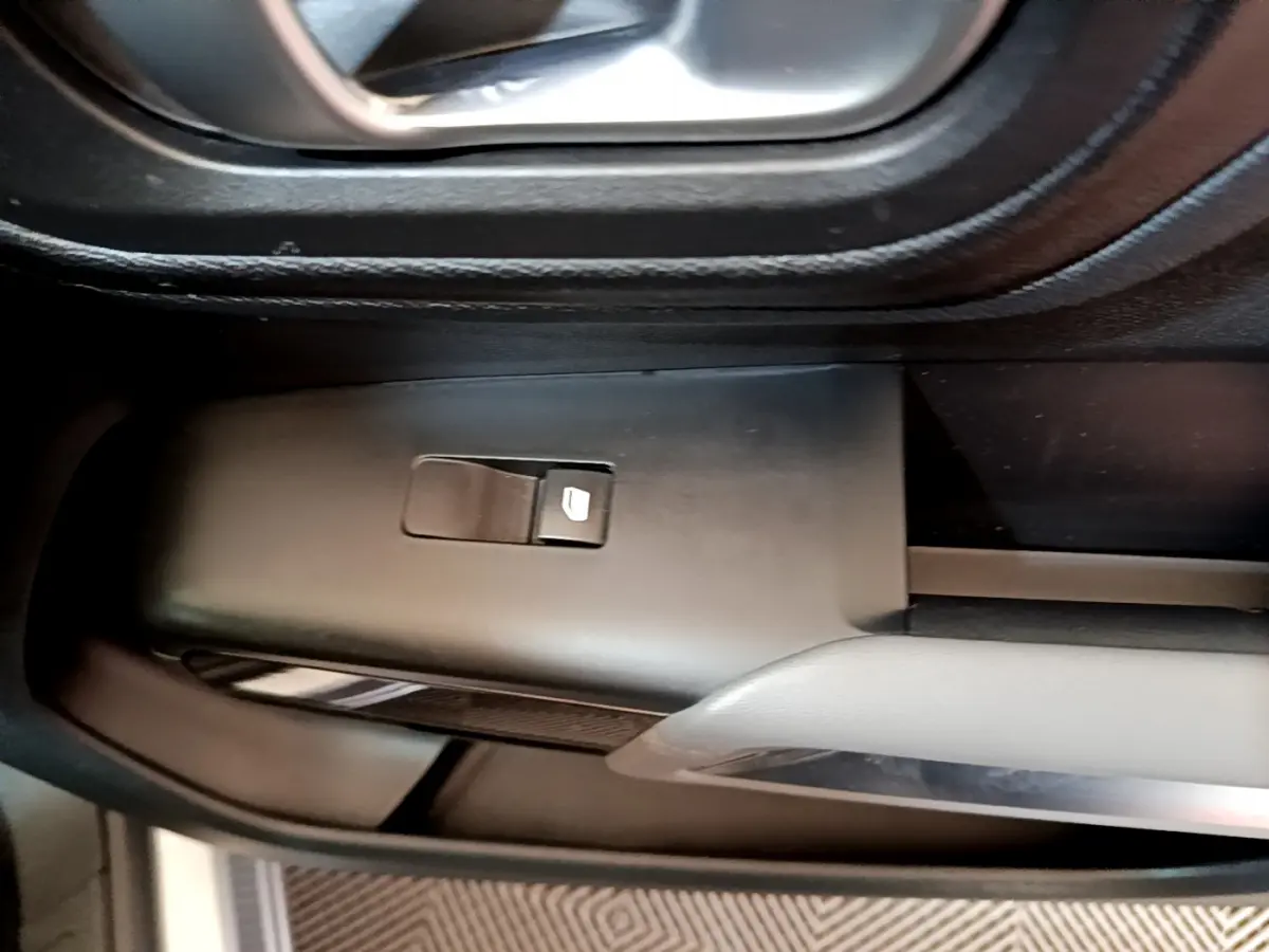 Gros plan sur le bouton de commande de vitre électrique côté gauche dans l'habitacle du Citroën C5 Aircross Hybrid 225 gris clair.