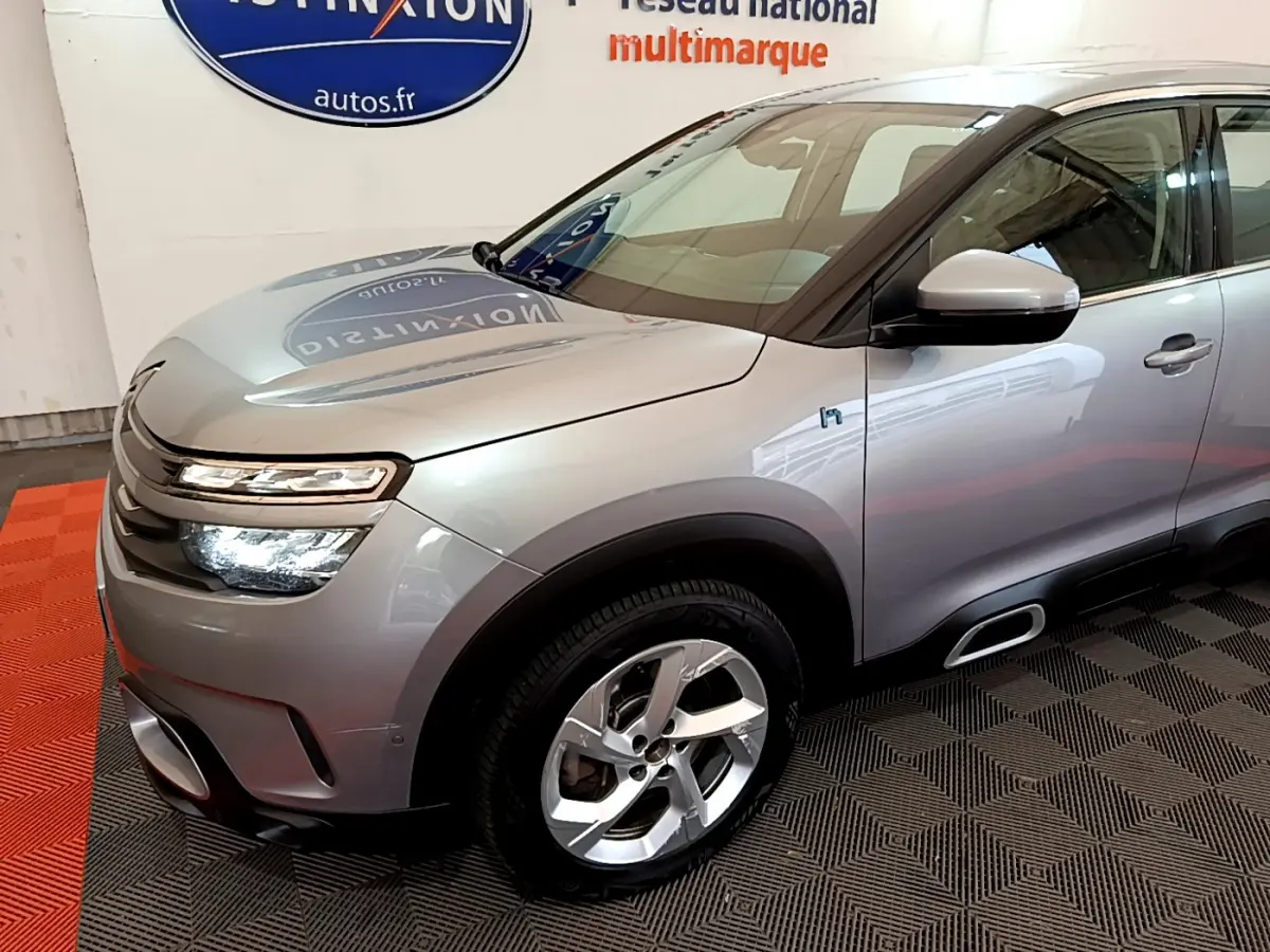 Vue 3/4 avant droit d'un Citroën C5 Aircross Hybrid gris clair avec phares LED et jantes alliage.
