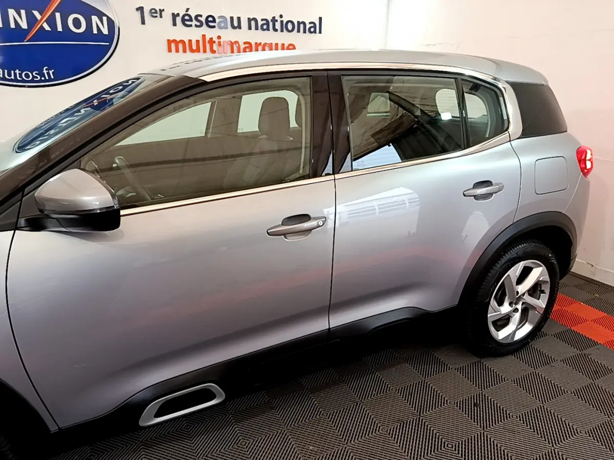 Profil côté gauche d'un Citroën C5 Aircross Hybrid gris clair, mettant en valeur ses lignes fluides et ses jantes modernes.
