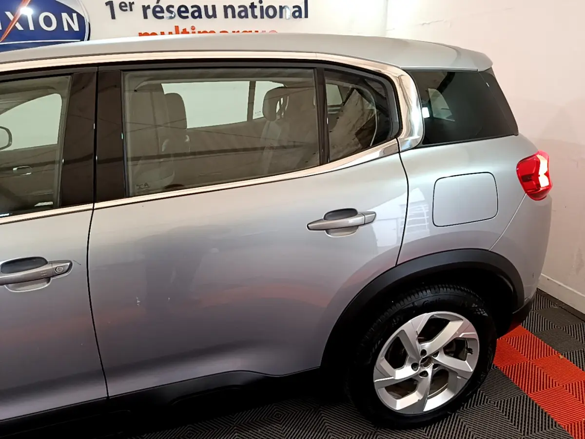 Vue latérale droite sur l'arrière d'un Citroën C5 Aircross Hybrid gris clair avec jante alliage et vitres teintées.