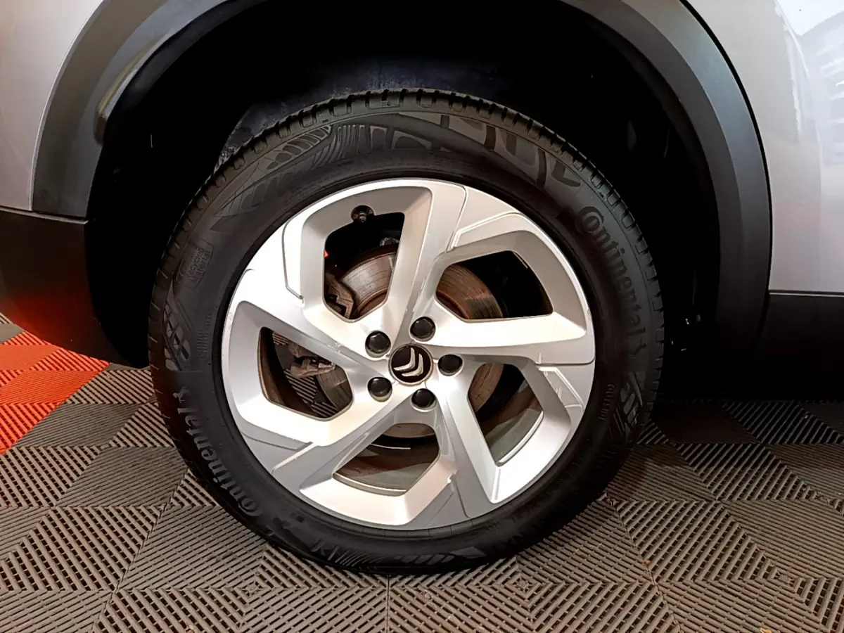 Gros plan sur la roue avant droite gris clair d'un Citroën C5 Aircross Hybrid 225 ë-EAT8 Business avec jante alliage cinq branches.