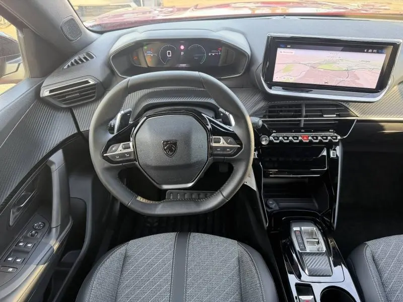 Vue intérieure avant du Peugeot 2008 Hybrid 2024 montrant le volant multifonction et l'écran tactile de navigation.